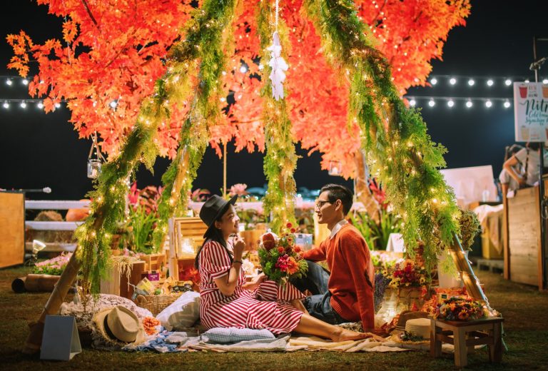 romantic-couple-sitting-amidst-illuminated-plants-field-night